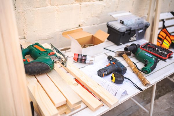 Screwdriver and wooden plank on a table outdoors.