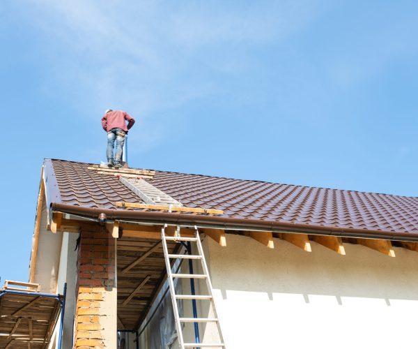 The master for the installation of ventilation pipes and the installation of the chimney of the furnace works on the roof of the house